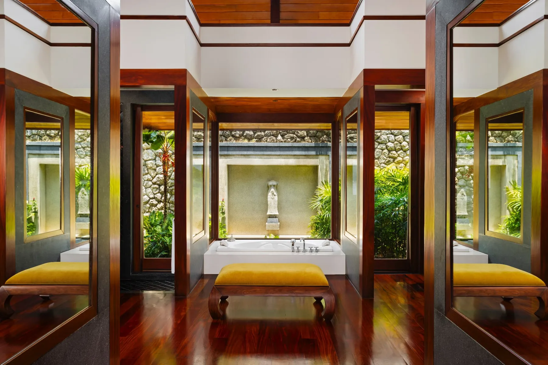 Ensuite bathroom with deep soaking tub framed by garden courtyards