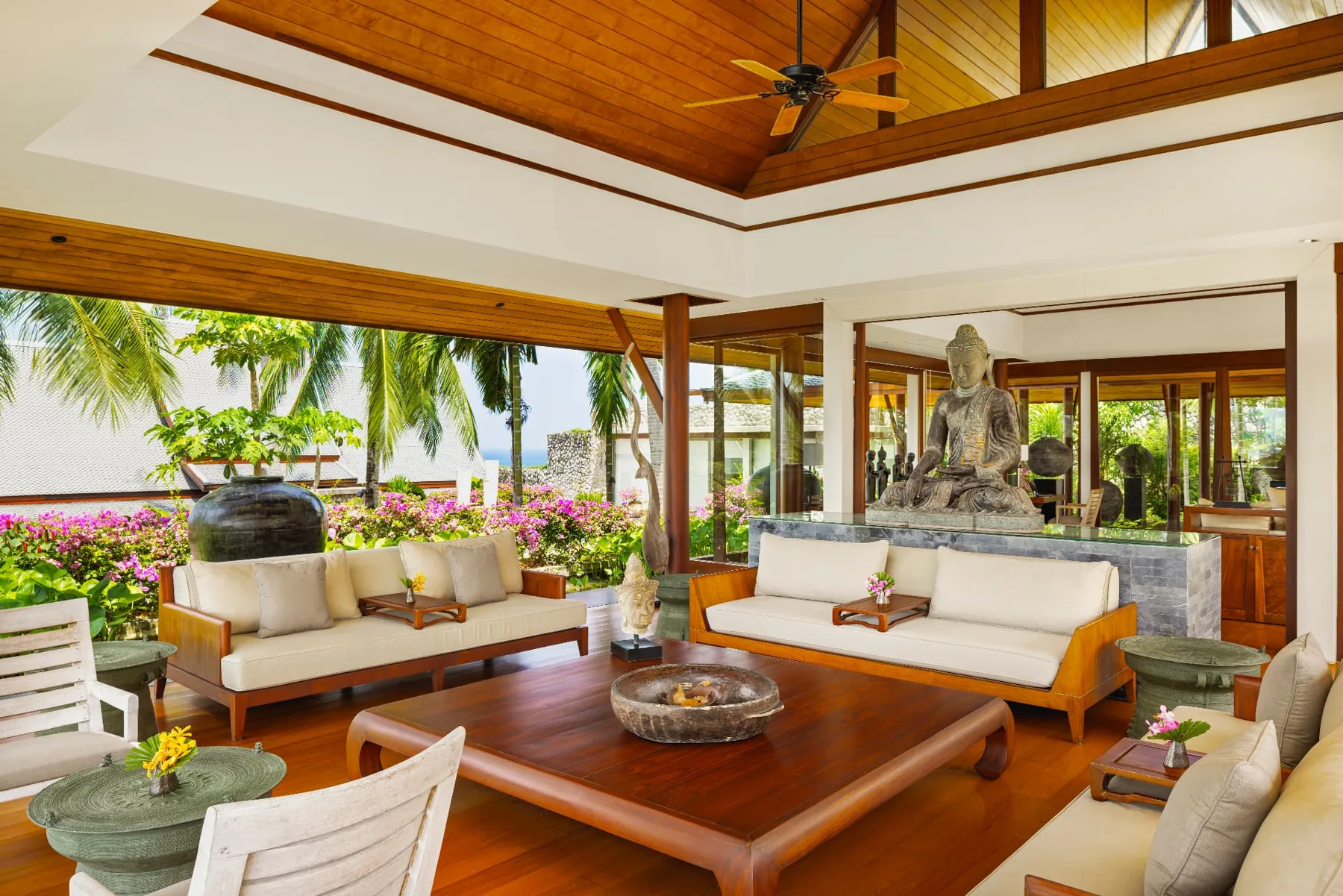 Open-air living pavilion with seated Buddha and ocean view
