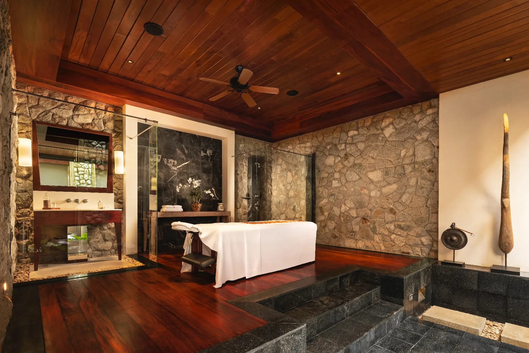Spa treatment room with stone walls, teak floors and rain shower